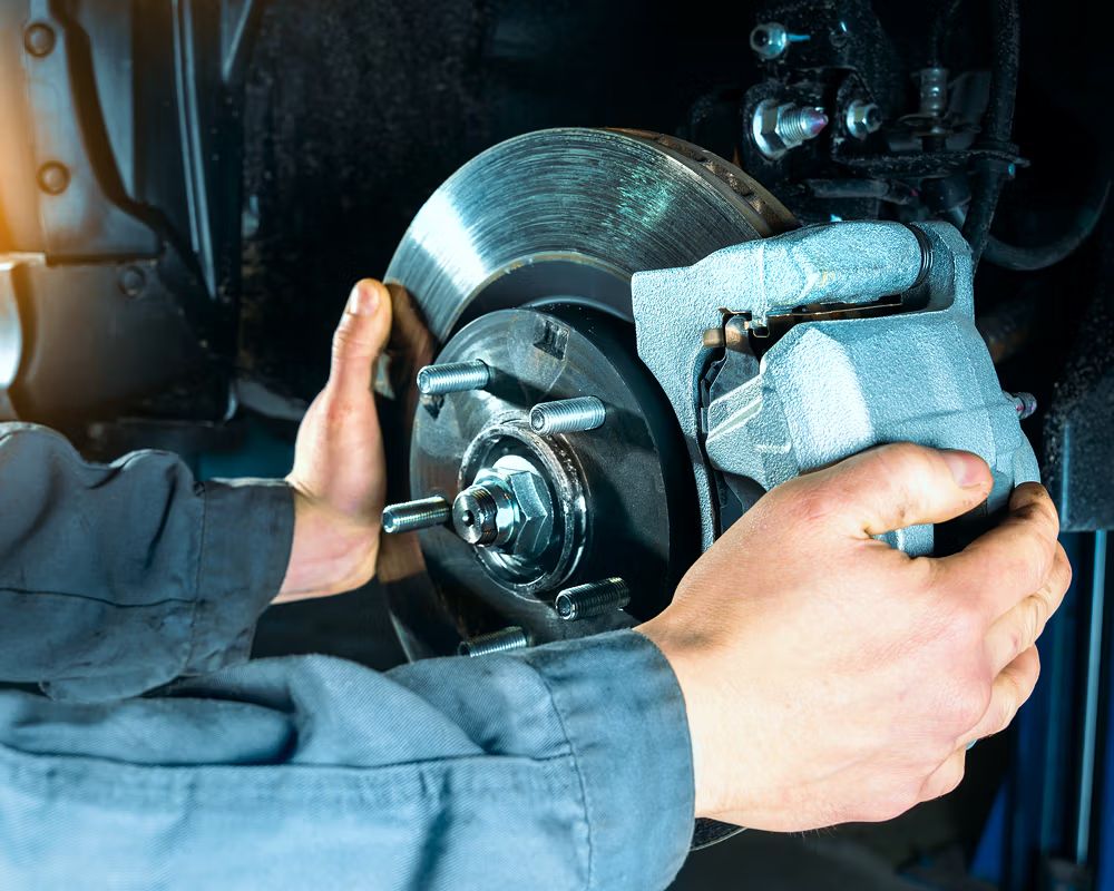 Brake calliper being refitted over a new disc during a brake replacement